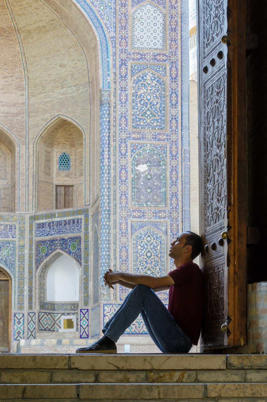 A man sits on the steps of Kalan Mosque in Bukhara, Uzbekistan