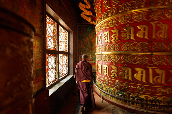 A monk turns a prayer wheel