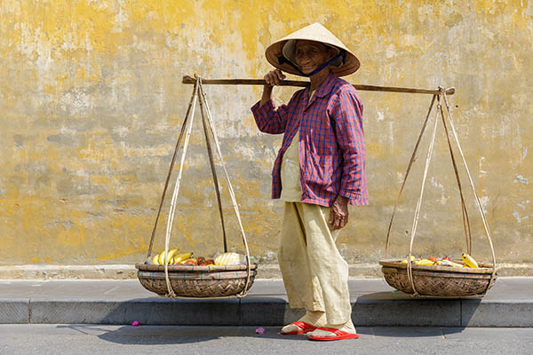 A street vendor walks through Hoi An's old town, Vietnam.