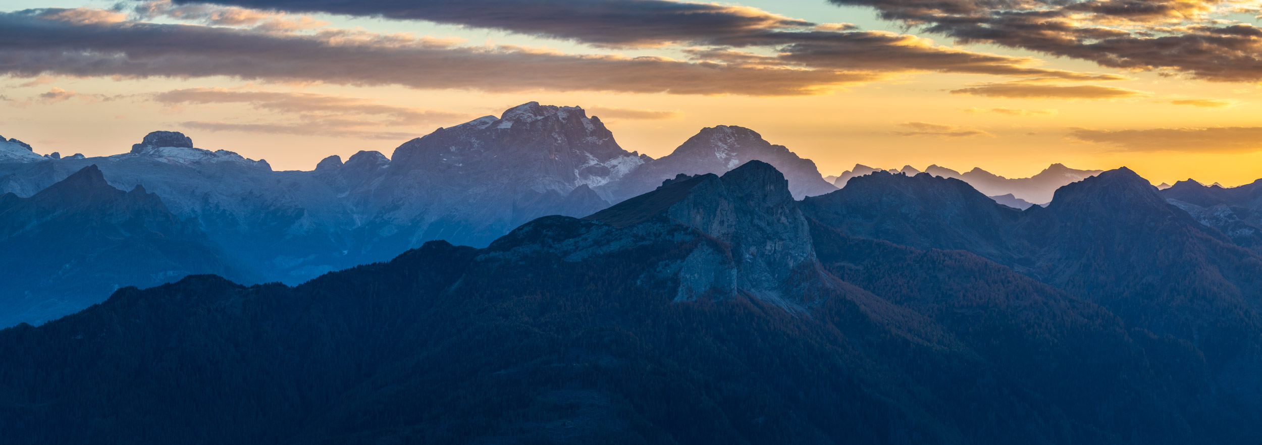 Panorama of the evening light illuminating the high mountains of the Dolomites around Passo Giau in northern Italy.