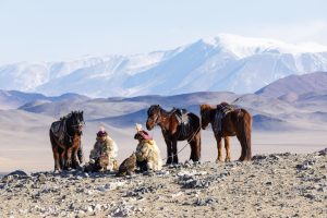 Two Kazak Mongolian eagle hunters in the vast wilderness of the Altai, Bayan Olgii, Mongolia.