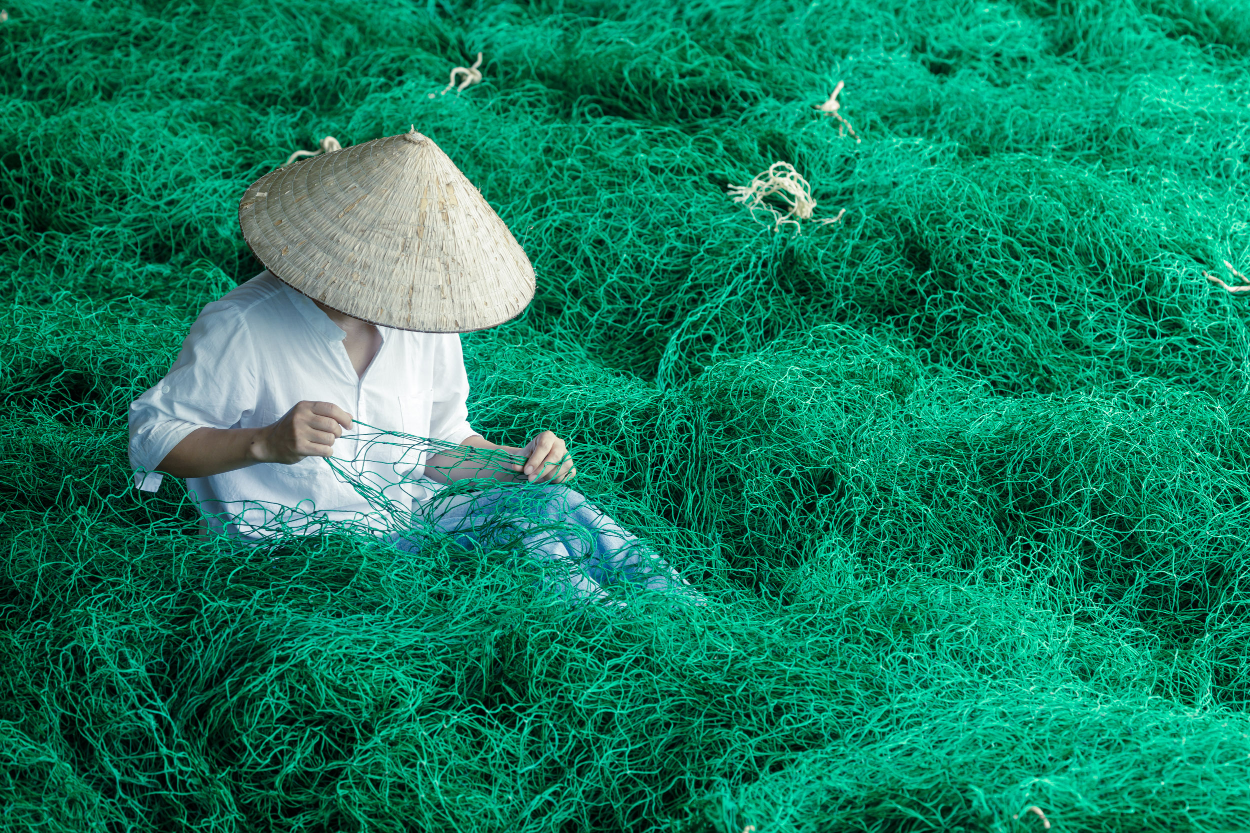 A young woman mending fishing nets in Vietnam.