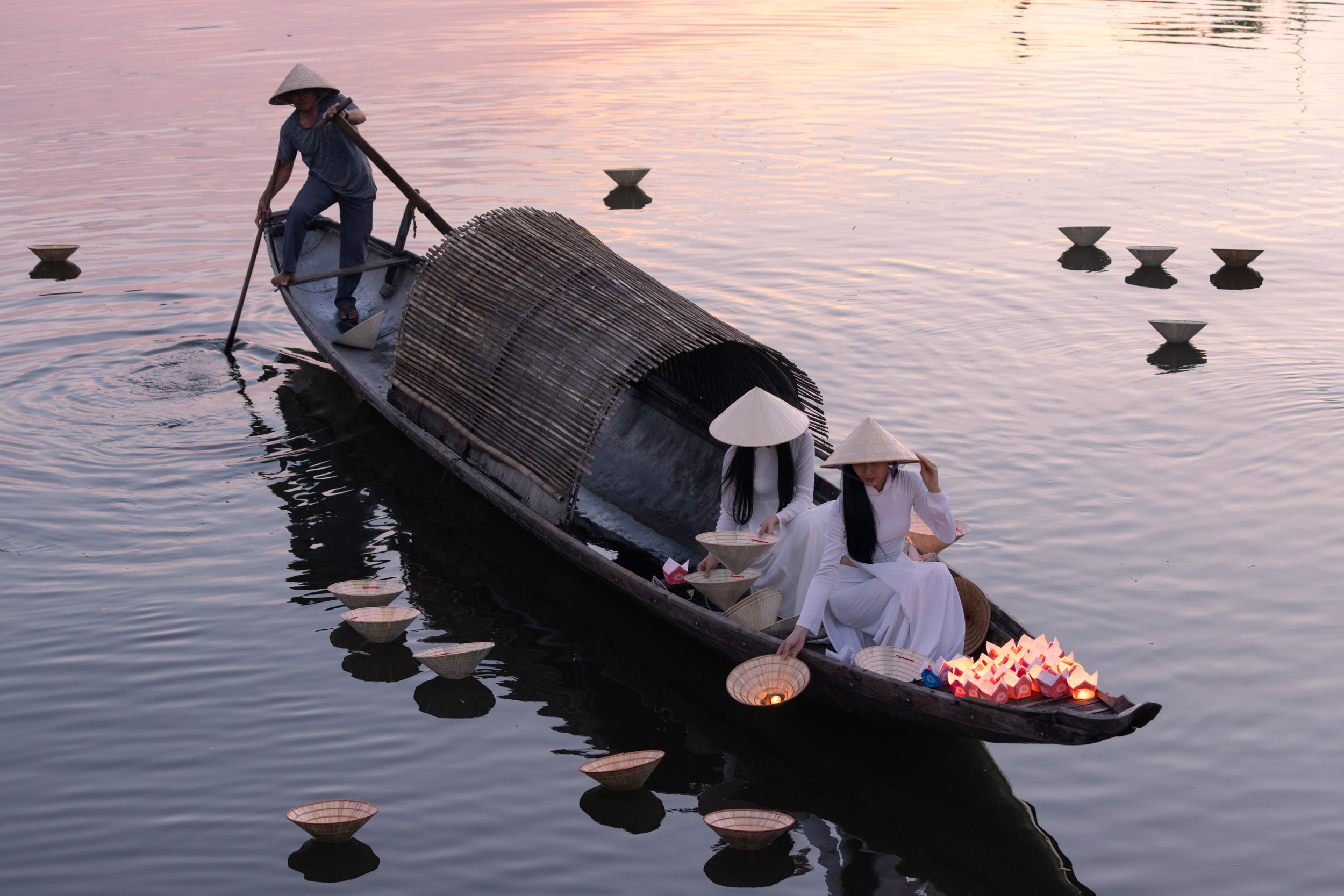 Two beautiful Vietnamese girls in Ao Dai (traditional dress) floating lanterns on the Perfume River in Hue, Vietnam.