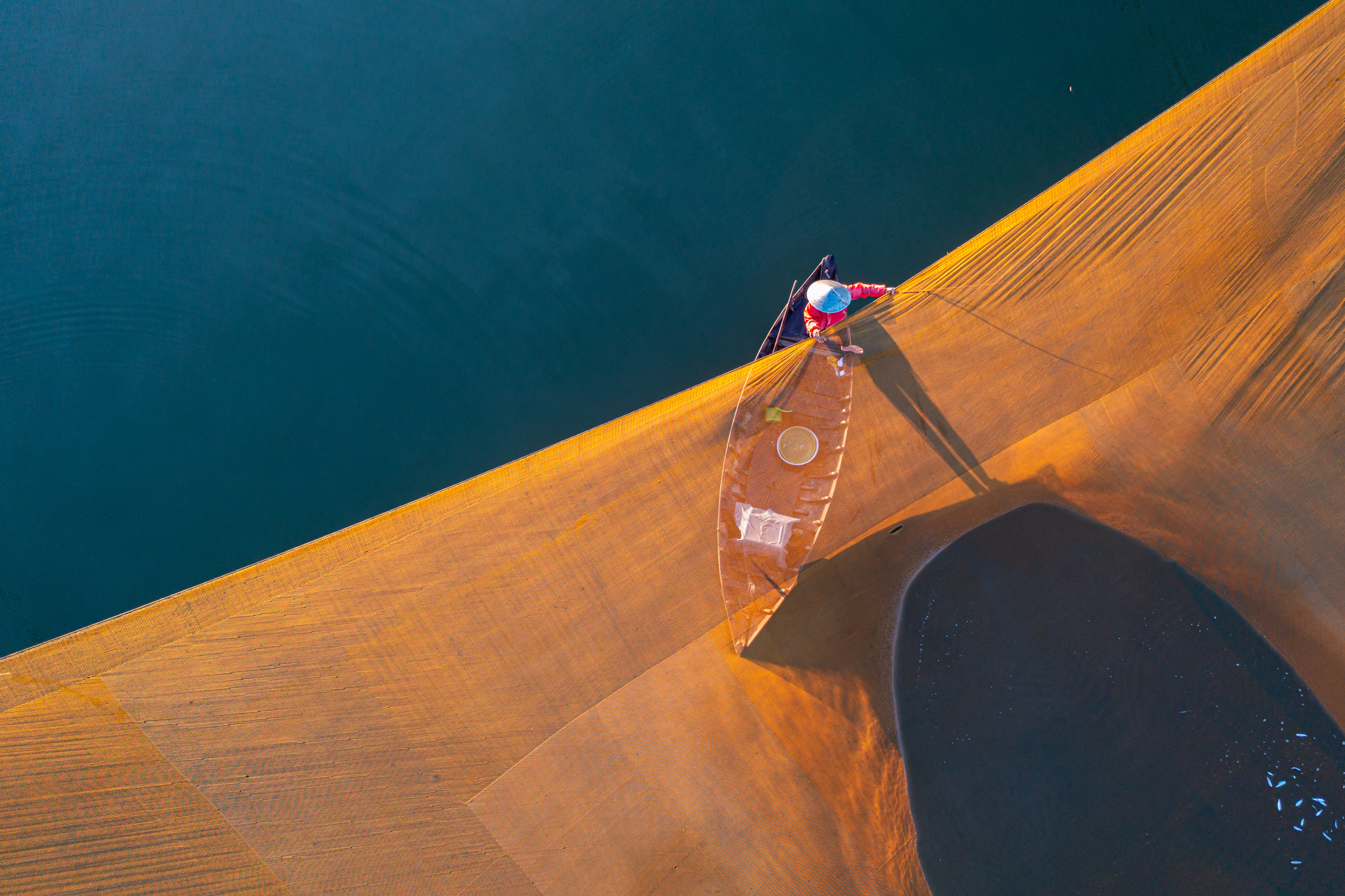 A fisherman tends to his early morning catch on the river near to Quang Nam, Vietnam.