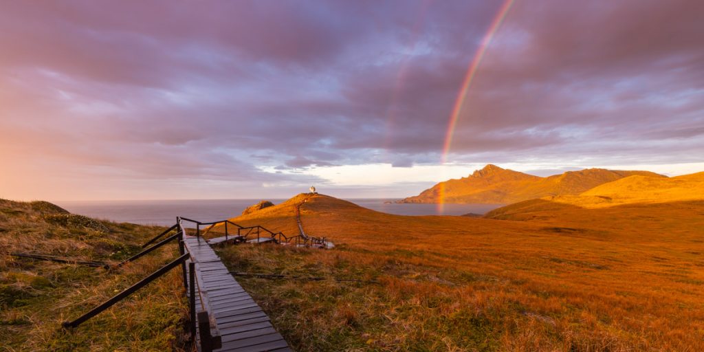 A firey sunrise and double rainbow across Hornos Island or the Isla Hornos in Chile.