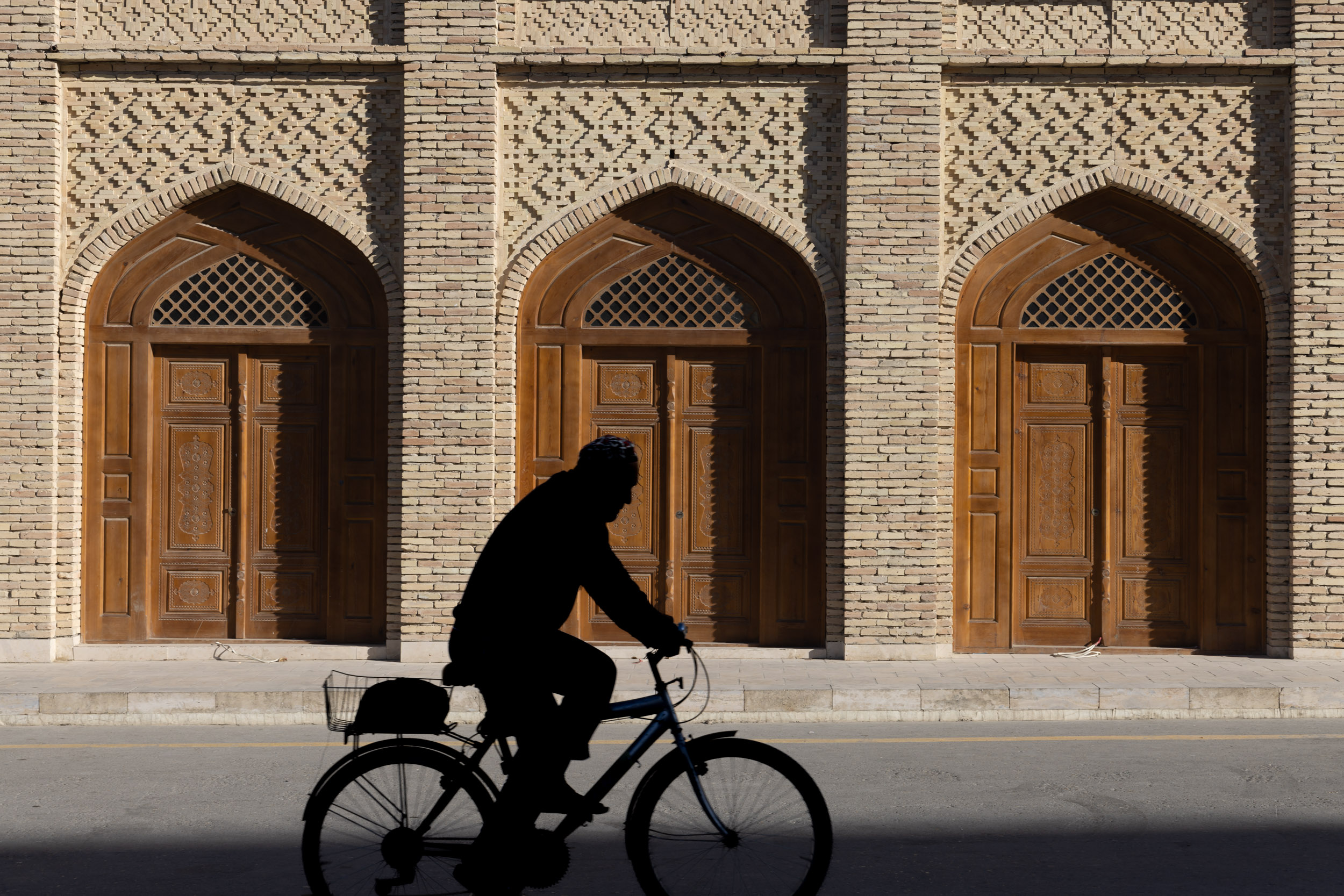 Silhouette of a man cycling past Poi Kalyon Square in Bukhara’s old town, Uzbekistan.