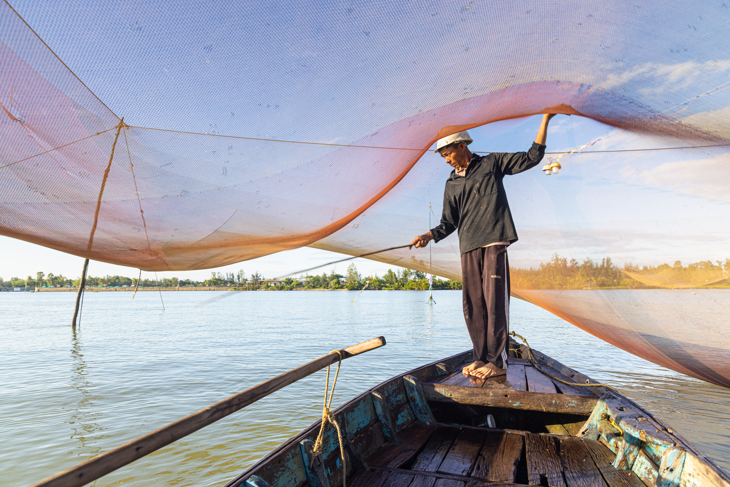 A fisherman at work during sunrise on the Thu Bon river near to Hoi An, Quang Nam, Vietnam.