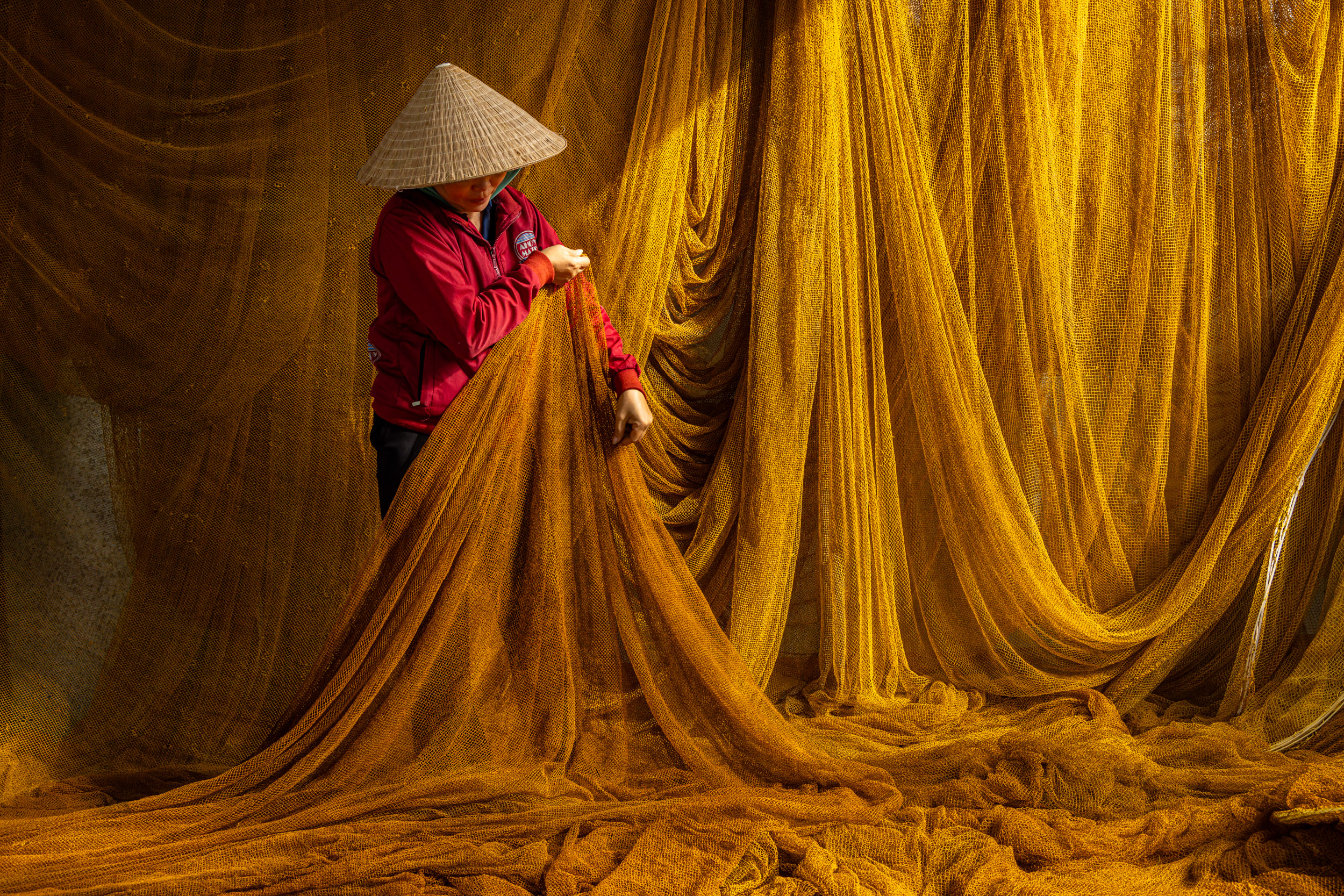A Vietnamese woman arranges yellow fishing nets in south Central Vietnam.