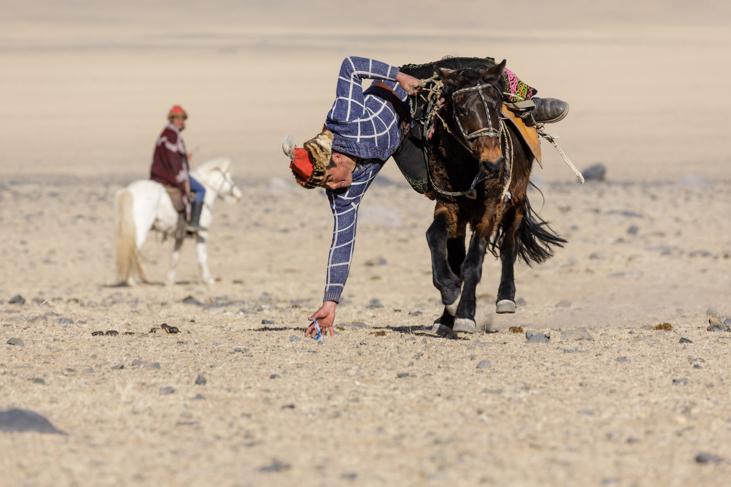 A Kazakh Mongolian eagle hunter plays the game of Tenge Iluat.