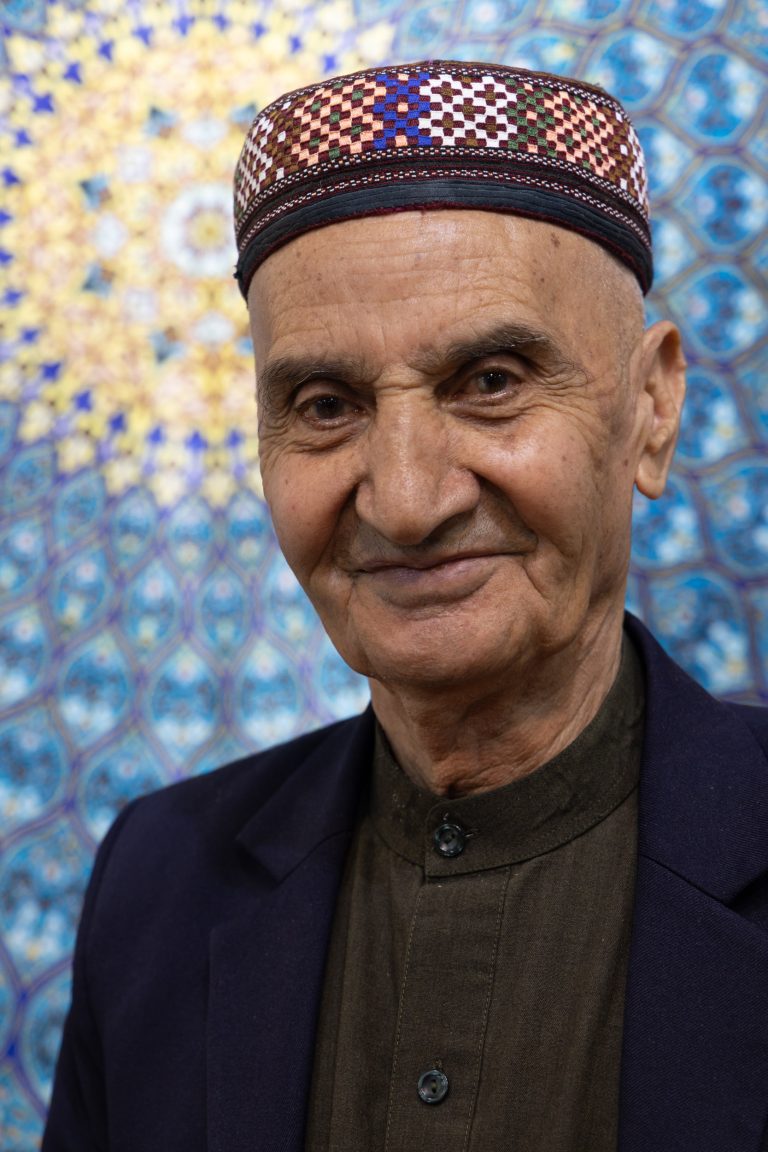 Portrait of an Afghan carpet maker posing against his stunning carpets in Samarkand, Uzbekistan.
