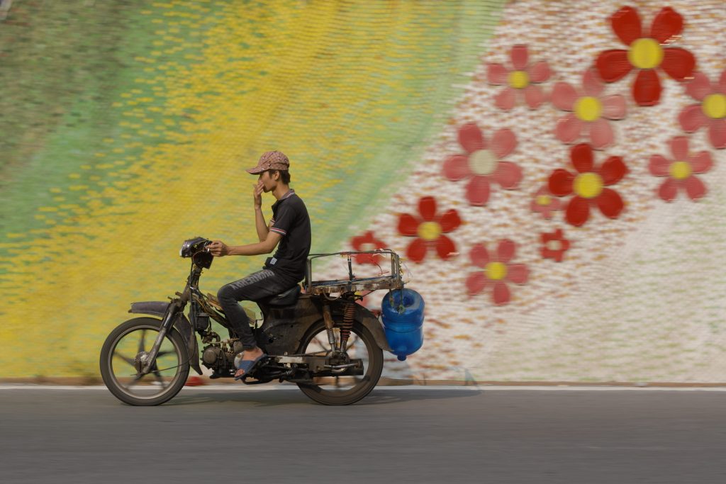 A motorcycle passes the mosaic wall in Hanoi. Taken during Vietnam photo tour in June.