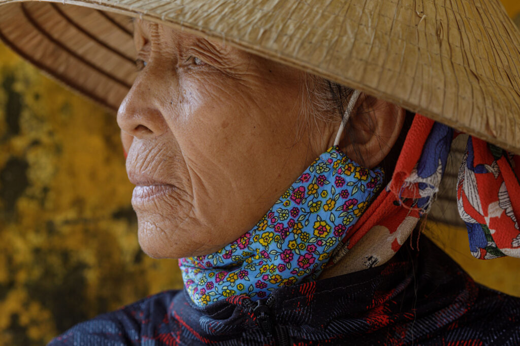 An Vietnamese woman peers out from under her traditional non la hat in Hoi An. Taken during Vietnam photo tour workshop.