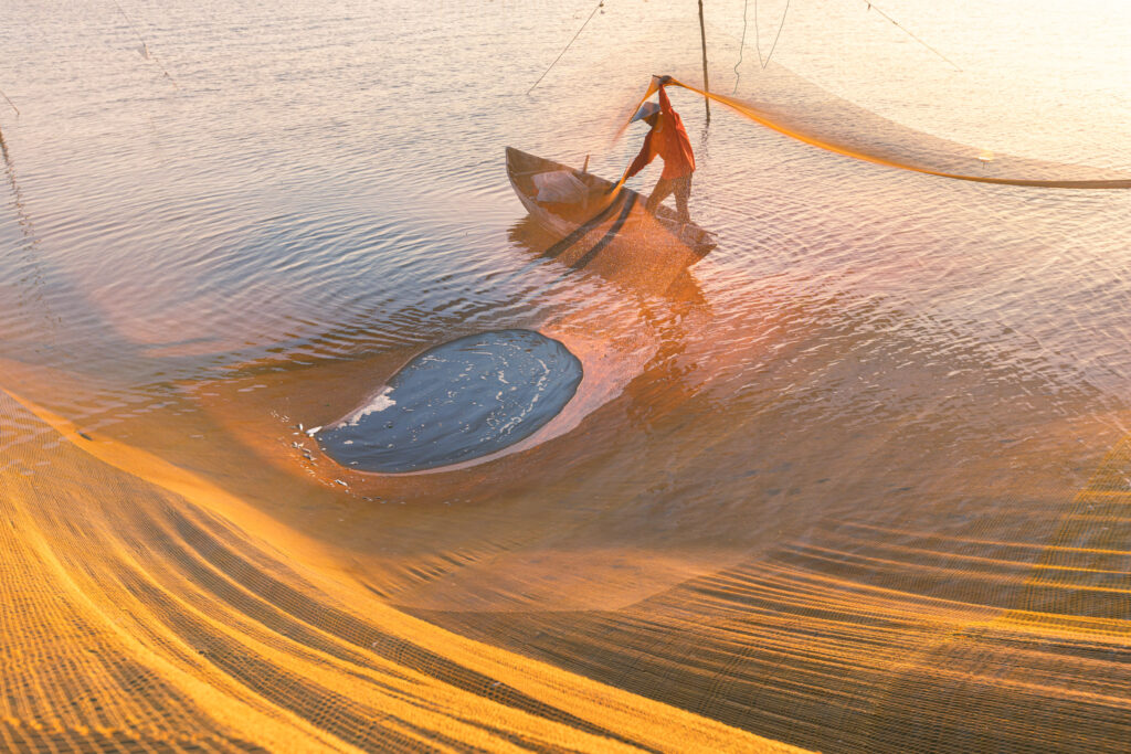 A fisherman at work during sunrise on the Thu Bon river near in Vietnam. Taken during Vietnam photo tour workshop.