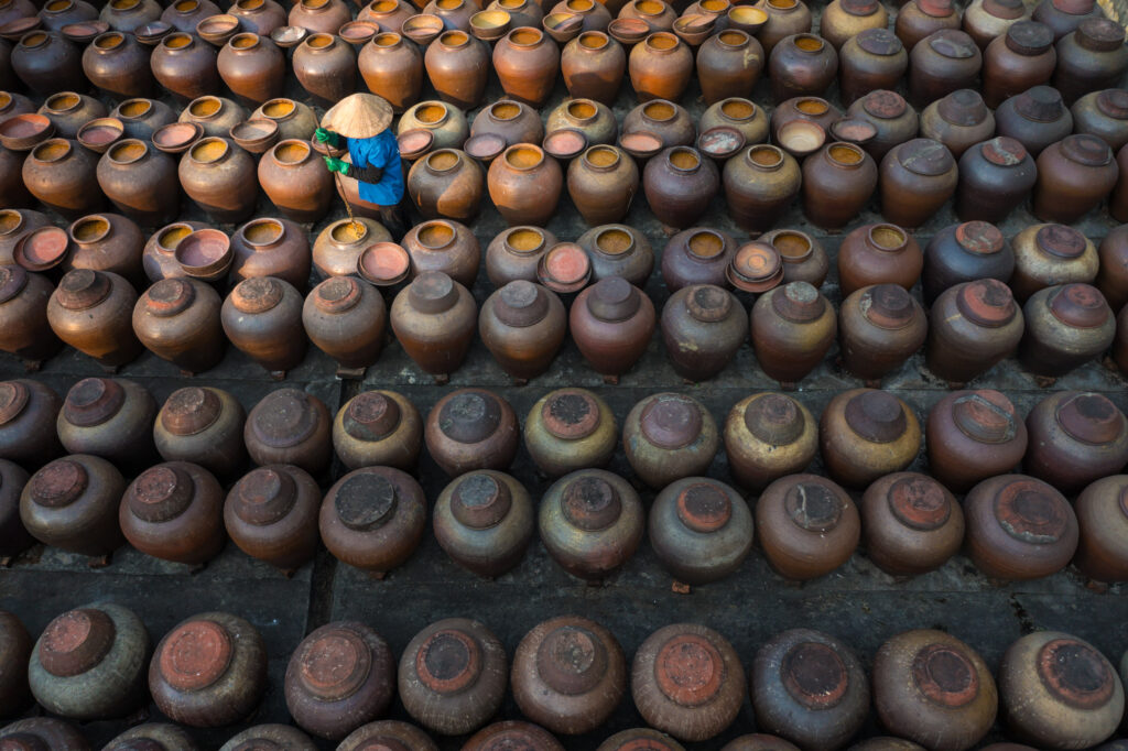 Aerial drone point of view of a worker preparing soybean or Ban soya sauce in Hung Yen. Taken during Vietnam photo tour and workshop.